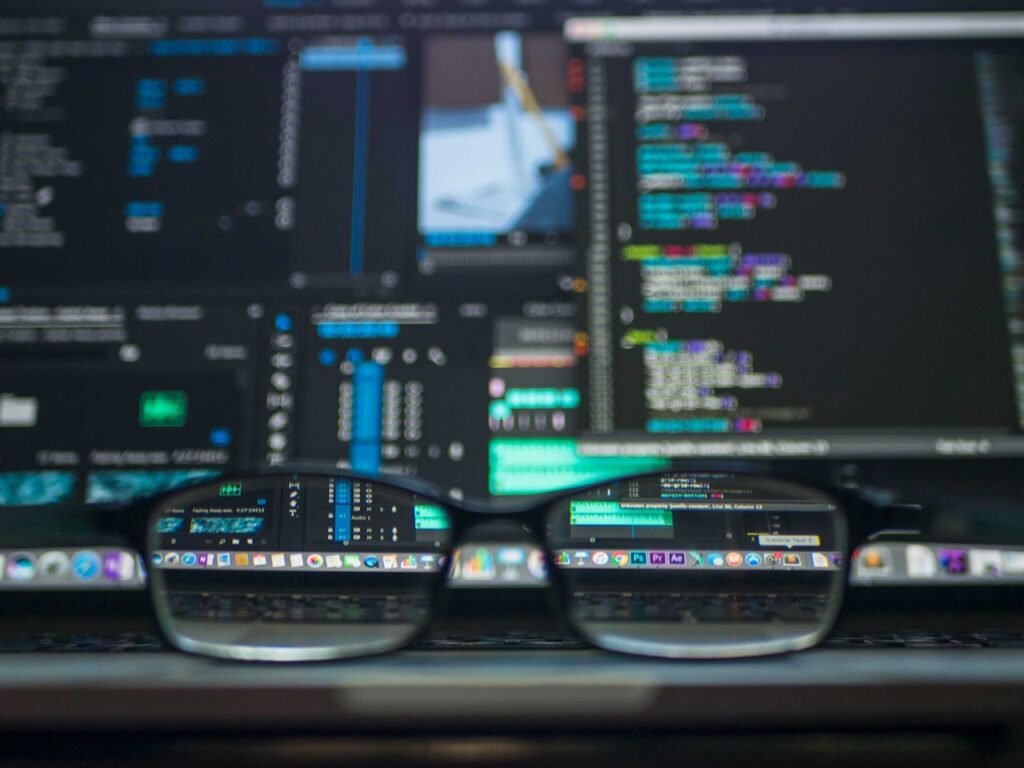 Eyeglasses reflecting computer code on a monitor, ideal for technology and programming themes.